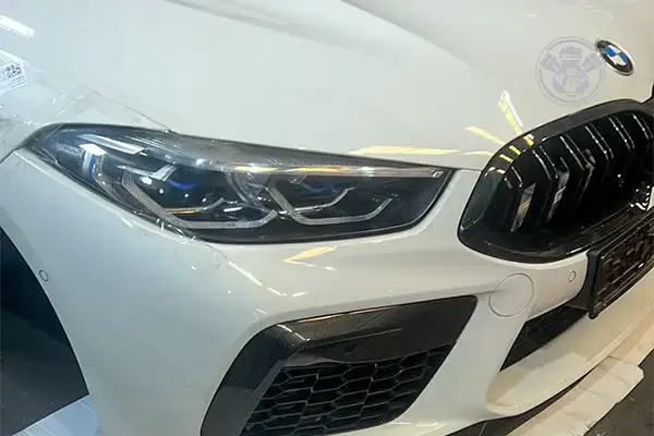واجهة أمامية بيضاء لسيارة BMW تضم شمعة وشبكًا وصدامًا