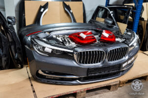 واجهة BMW داكنة بشبك مزدوج وأنوار أمامية وفوقها فانوسان أحمران وخلفها أجزاء بودي مع شعار محرك اليخت