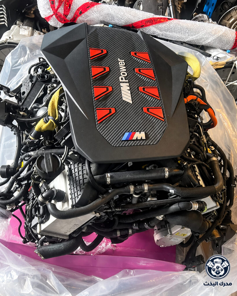 محرك بغطاء M Power أسود بتفاصيل حمراء وسط تغليف شفاف مع شعار محرك اليخت
