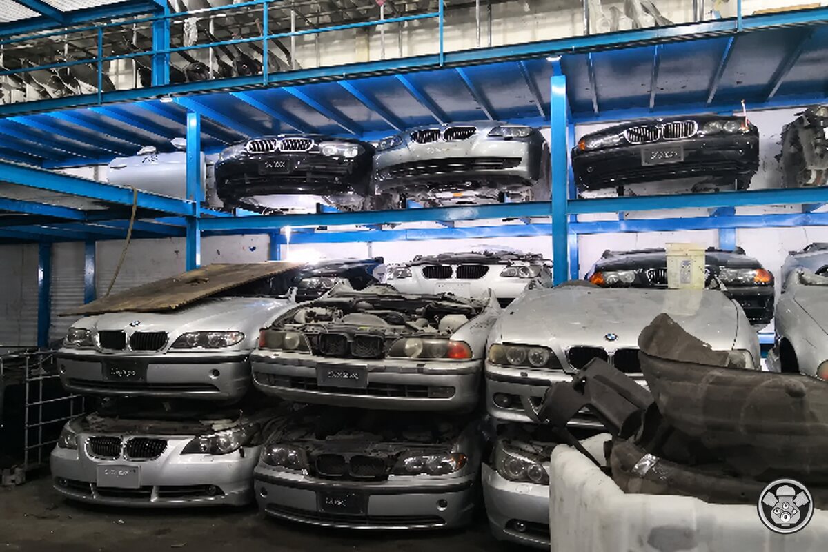 واجهات سيارات BMW فضية وداكنة على رفوف معدنية زرقاء داخل مستودع