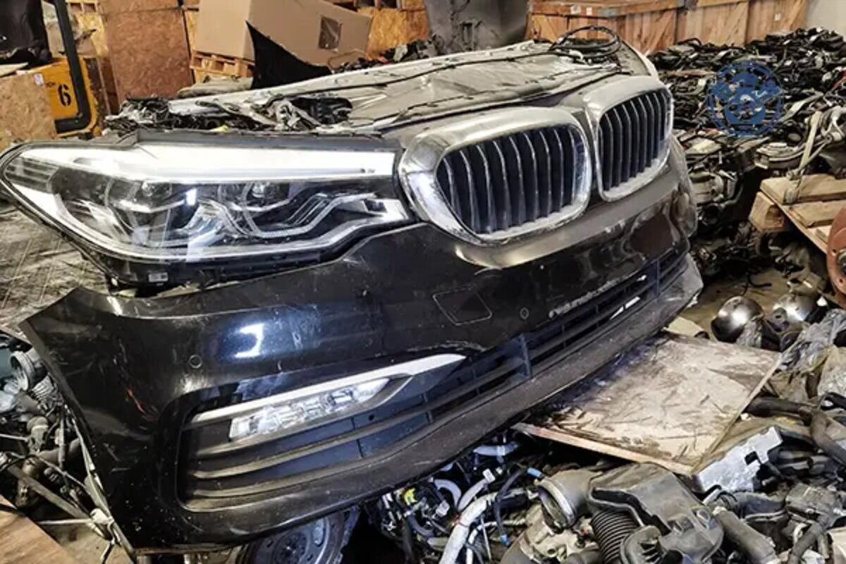 واجهة BMW داكنة بشبك ومصباح وصدام على قاعدة داخل مستودع قطع