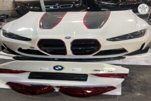 واجهات وأجزاء هيكل BMW بيضاء بأنوار وشبكات أمامية ومصابيح خلفية داخل مستودع