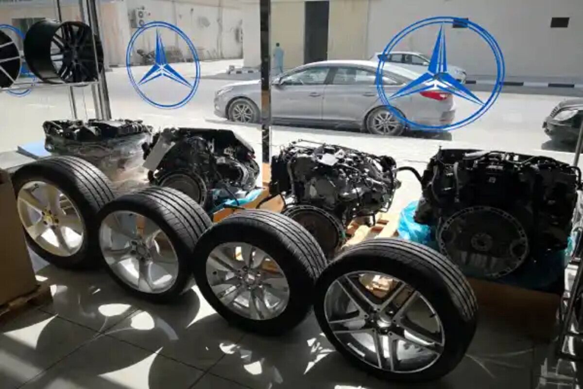 عجلات ووحدات ميكانيكية في معرض مع نجوم مرسيدس زرقاء معلقة خلفها